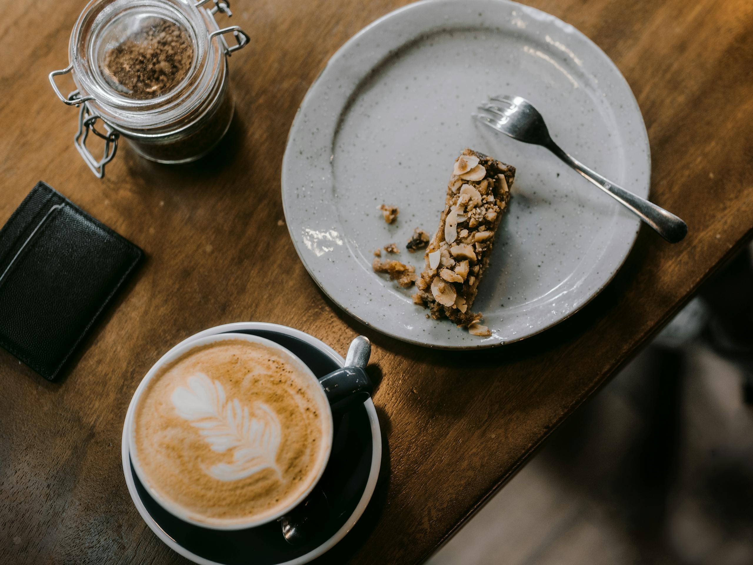Enjoy a relaxing coffee moment with a cappuccino and nut bar on a rustic wooden table.